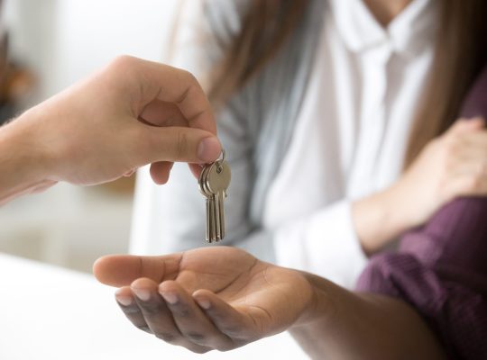 Realtor giving african customer keys, couple buying new house, c